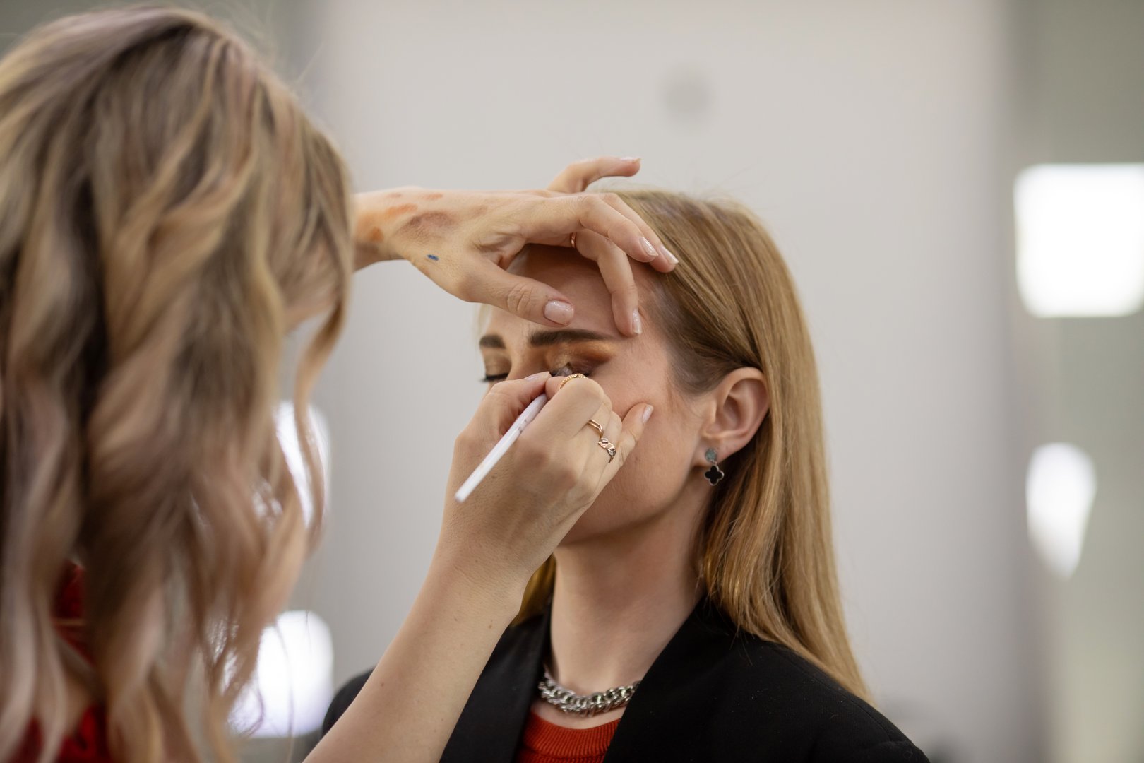 Businesswoman getting makeup done by makeup artist. Beauty salon.