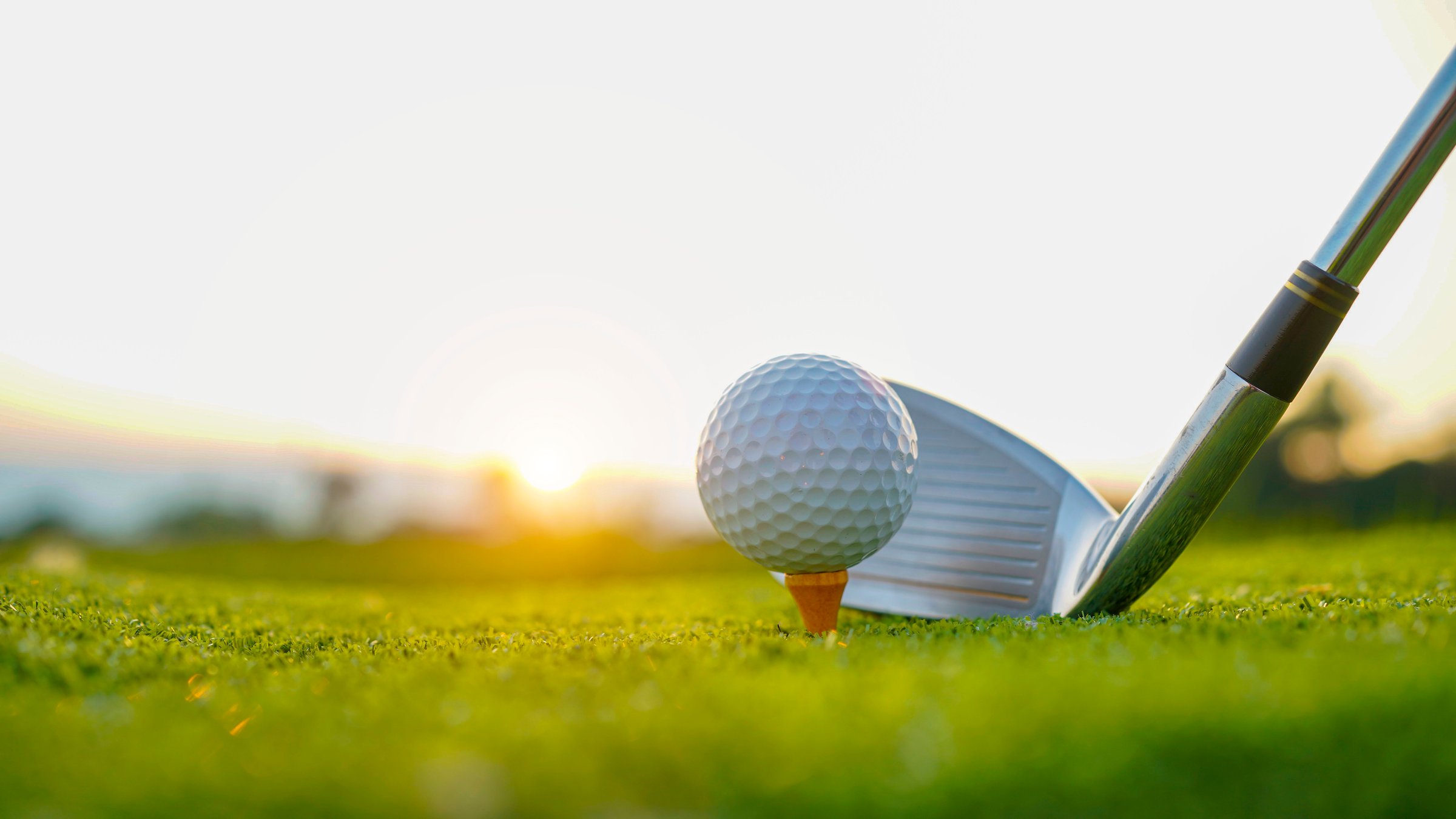 Golf clubs and golf balls on a green lawn in a beautiful golf course with morning sunshine. Close up of golf equipment on green grass.