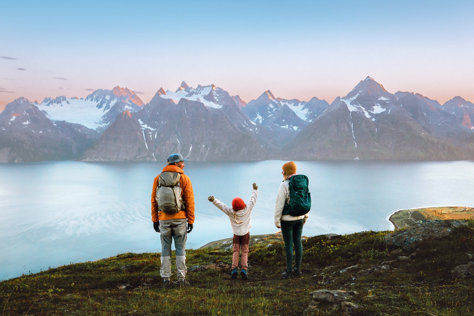 Family mother, father, and kid hiking together in Norway, travel lifestyle adventure vacations in Lyngen Alps mountains, parents and child on active outdoor backpacking trip healthy lifestyle tour