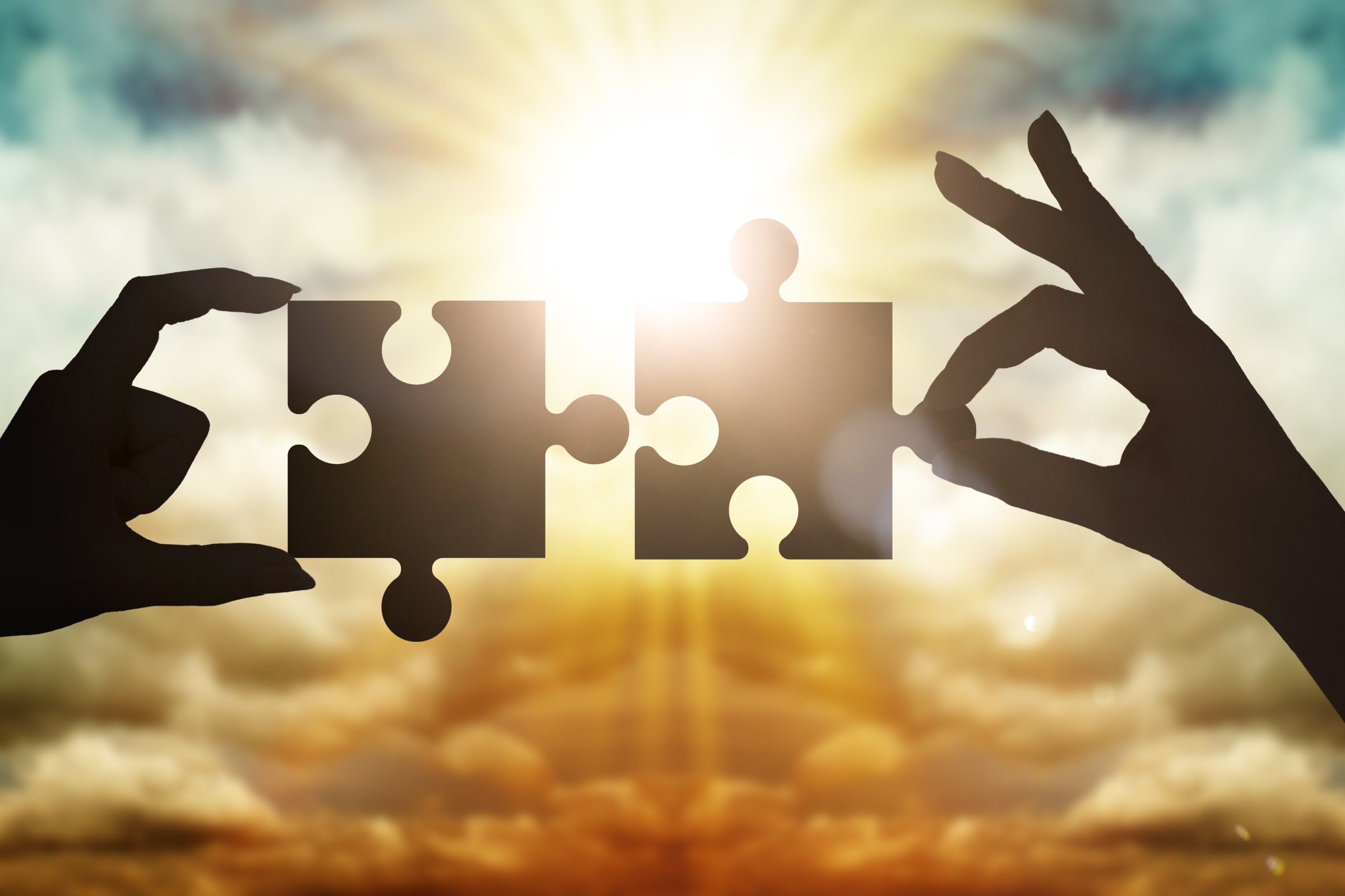 Hands collect gear in a puzzle against the sky in the sunset. Business concept idea, partnership, innovation, teamwork, cooperation