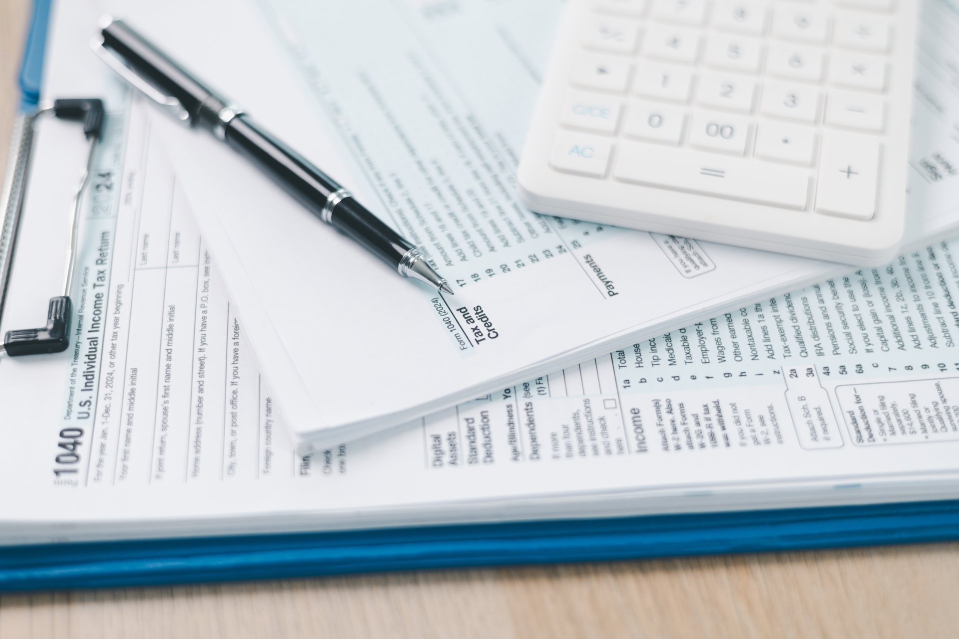 Concept of tax filing and accounting. Close up of US individual income tax return form with pen and calculator on office desk, symbolizing financial planning, budget management and payment accuracy.