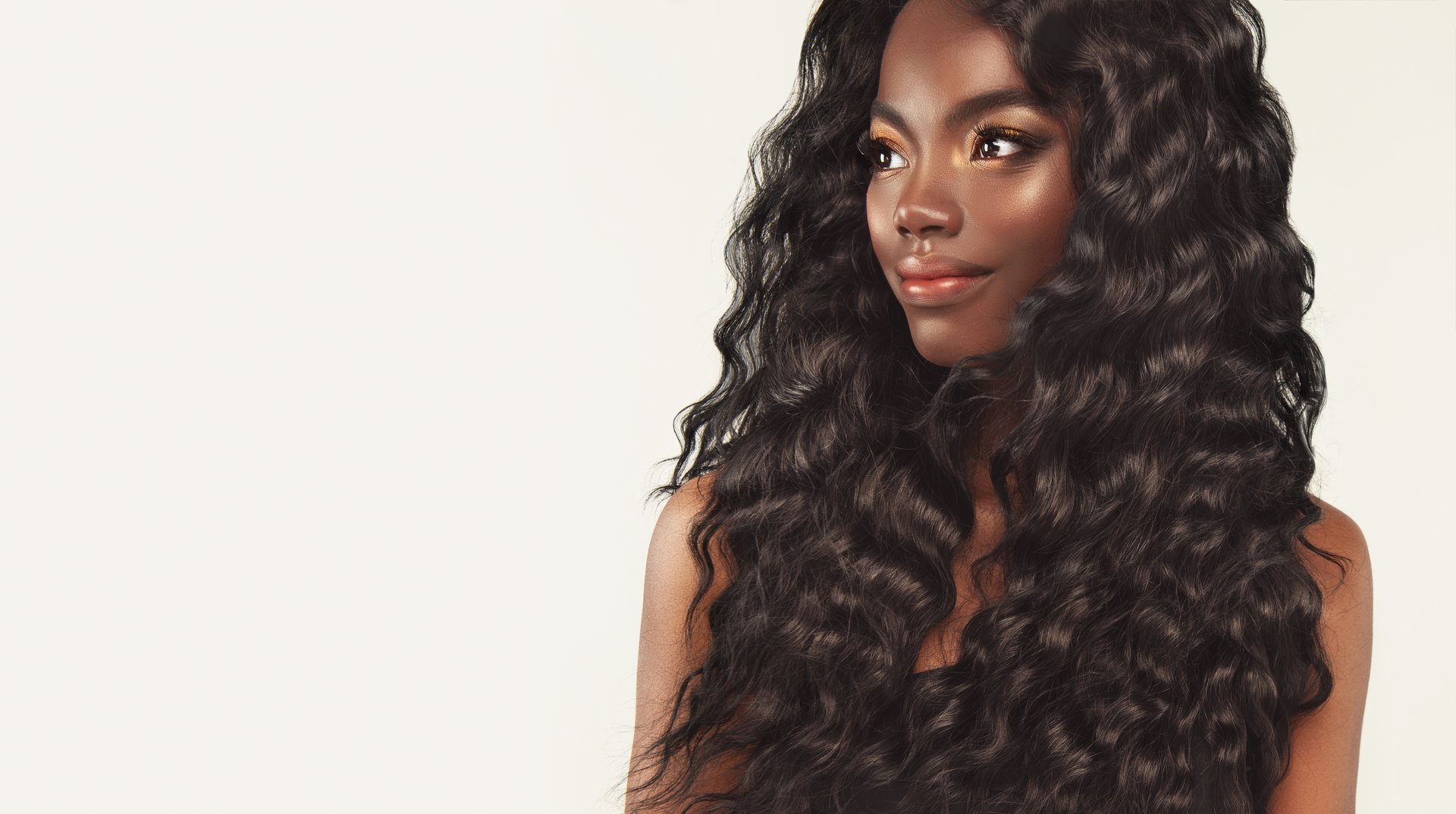 Gorgeous young black woman with long black wavy hair. Model dressed in elegant makeup.Girl with vibrant melanin-rich skin tone. Look full of kindness. Beauty hairstyle and fashion.