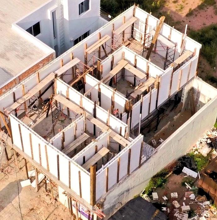 Aerial view of a building under construction with wooden scaffolding and partially completed walls.