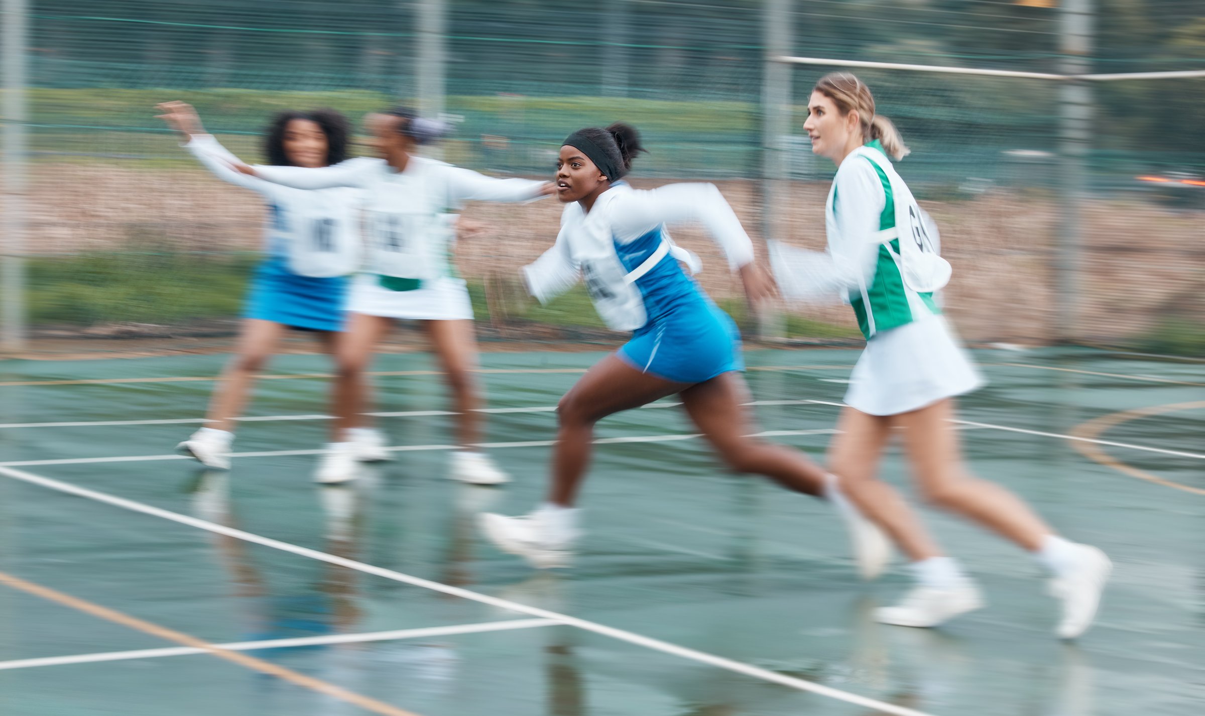 Sports, running and team netball competition, practice and women playing game, court challenge or action match. Fast motion blur, speed and group cardio workout, player teamwork and athlete training