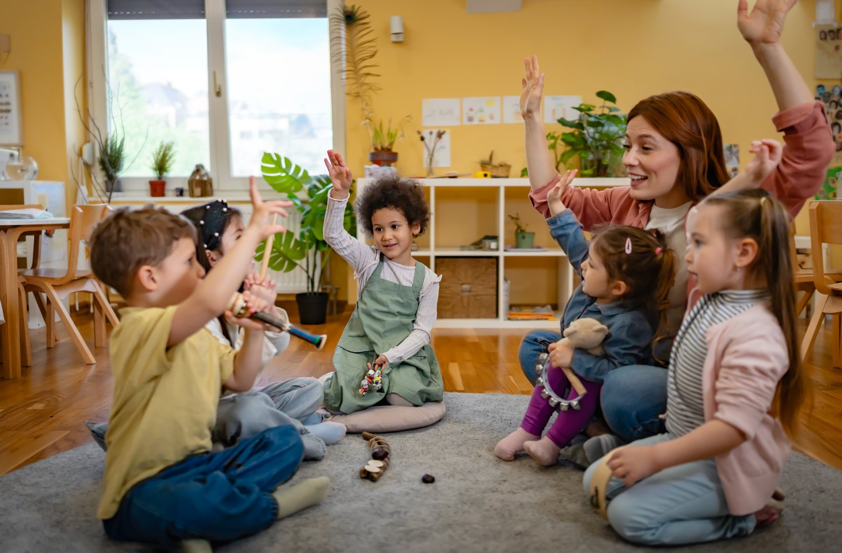 Multicultural group of preschool children playing musical instruments with a kindergarten teacher during a fun music activity in a bright, cheerful classroom