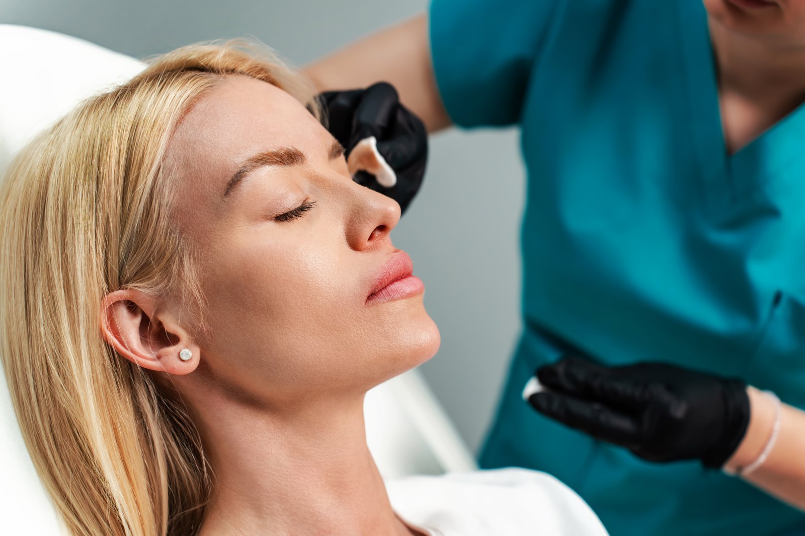 Attractive woman is getting a rejuvenating facial injections at beauty clinic. The expert beautician is filling female wrinkles with botulinum toxin injections or hyaluronic acid fillers.