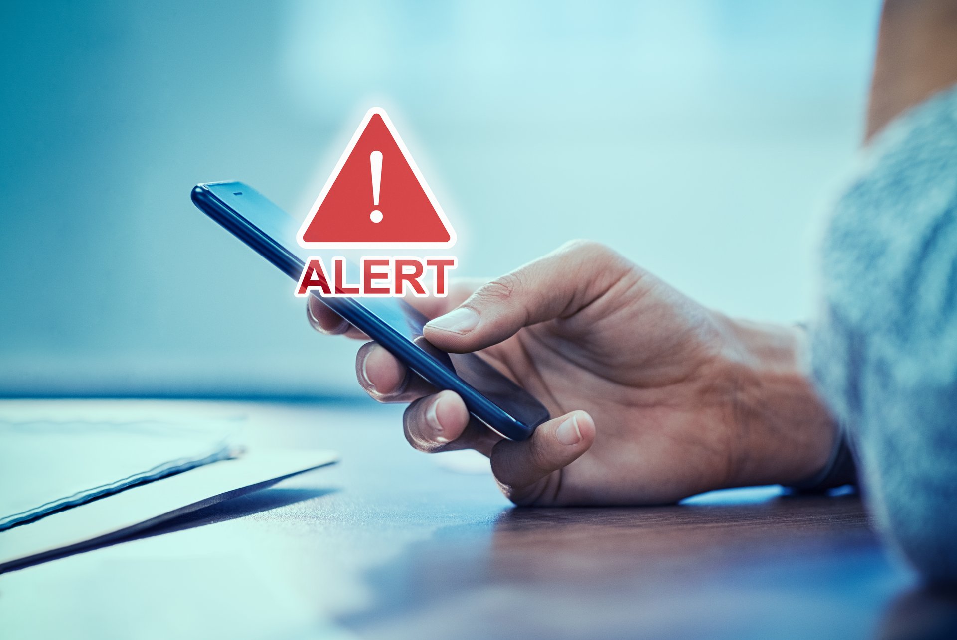 Emergency alert security message pop up on phone screen. Woman hand holding smartphone while receiving an official emergency alert notification from government.