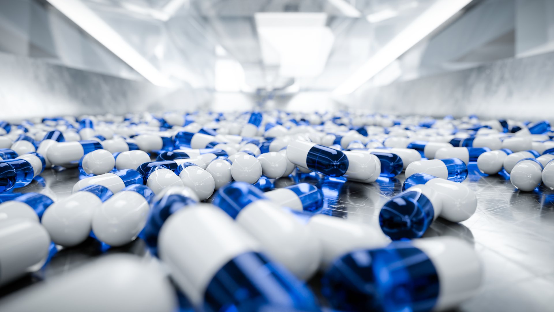 Blue and white capsules scattered on a shiny metallic surface