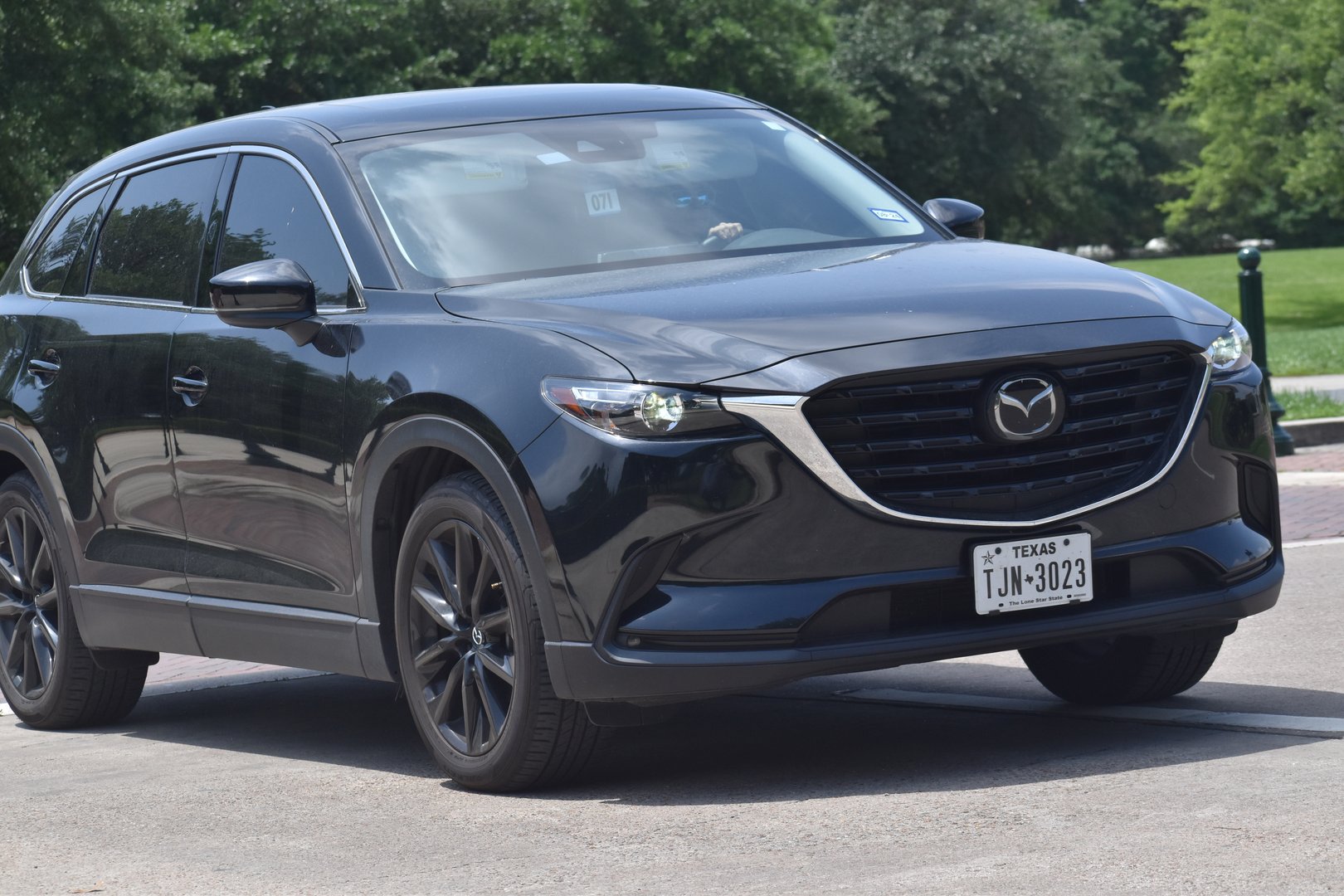 Houston, TX USA 4-29-2024 - A black Mazda CX+9 SUV cruising near a nature reserve
