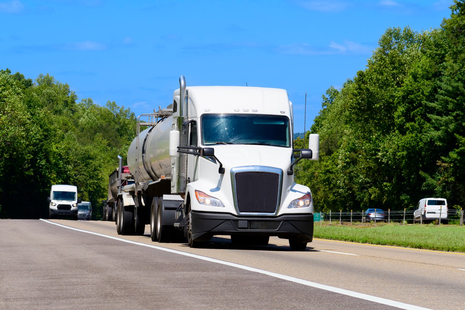 Horizontal shot of a white eighteen wheeler tanker truck on the interstate with copy space.