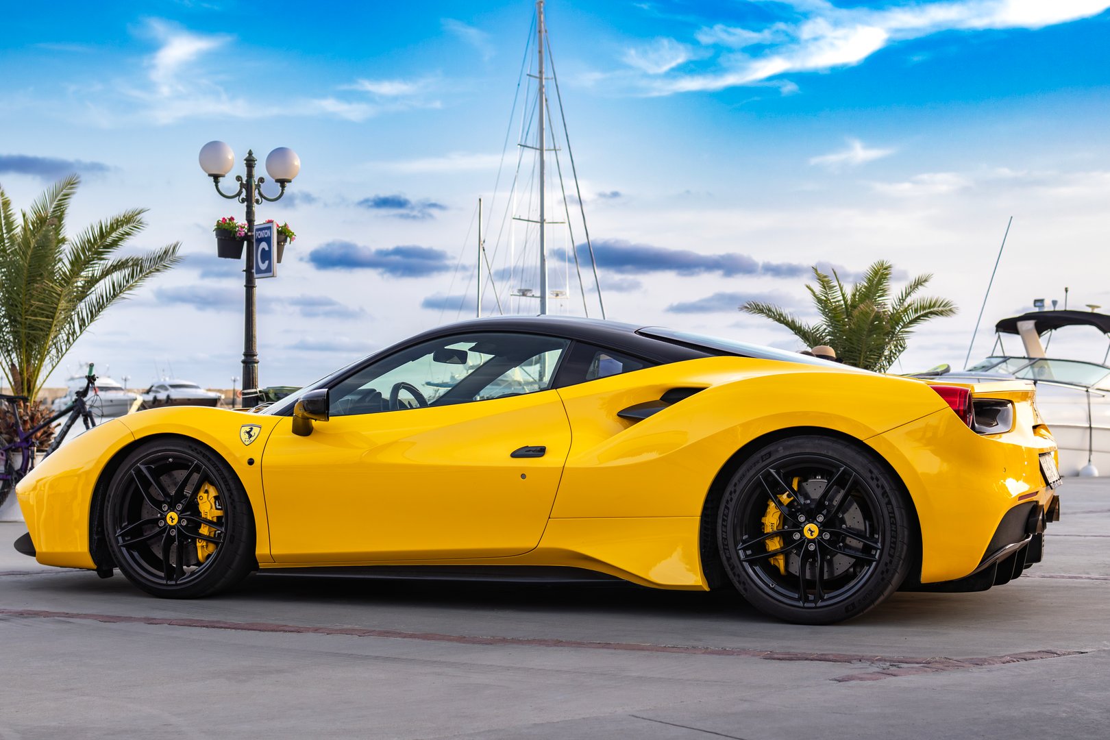 Yellow sports car Ferrari Spider on yacht marina at sunset