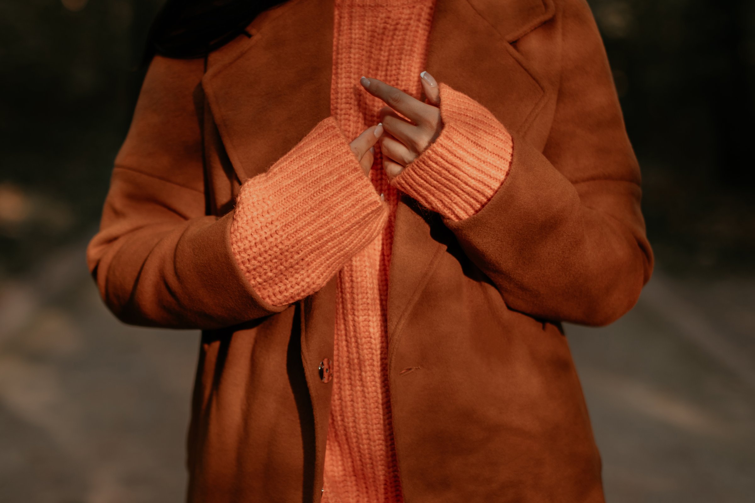 Fall clothes fashion details of knitted orange sweater and brown coat on a female figure, warm autumn comfortable outfit