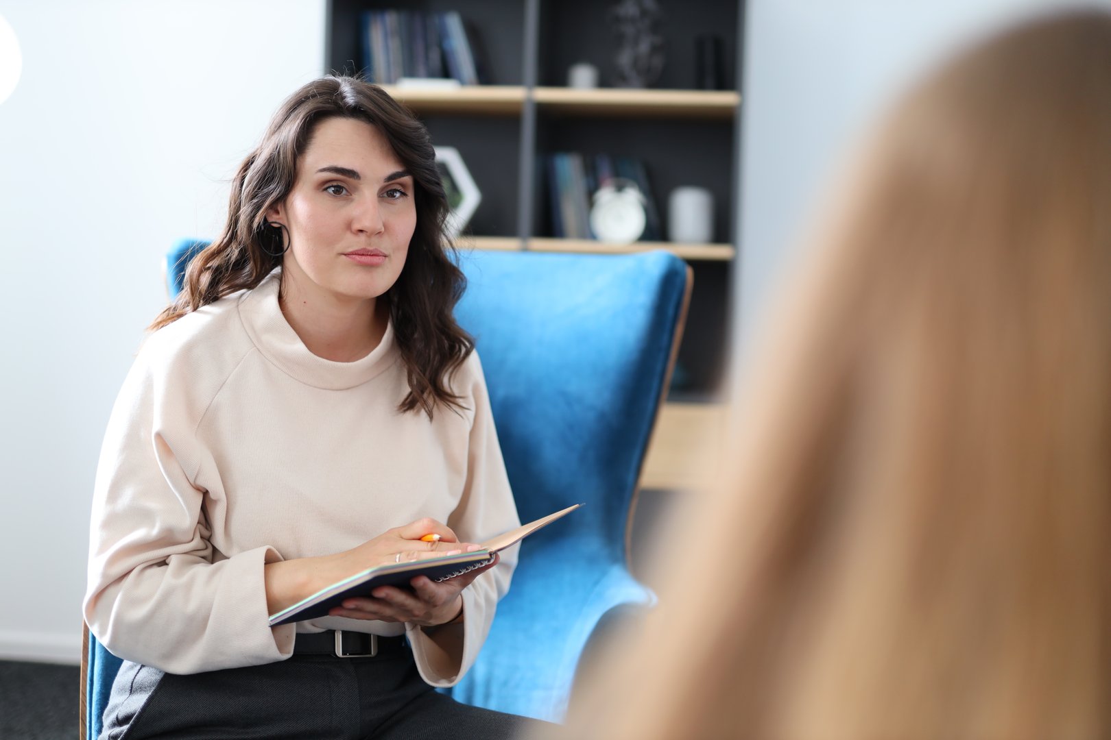 A woman is sitting in a chair with a notebook in her lap