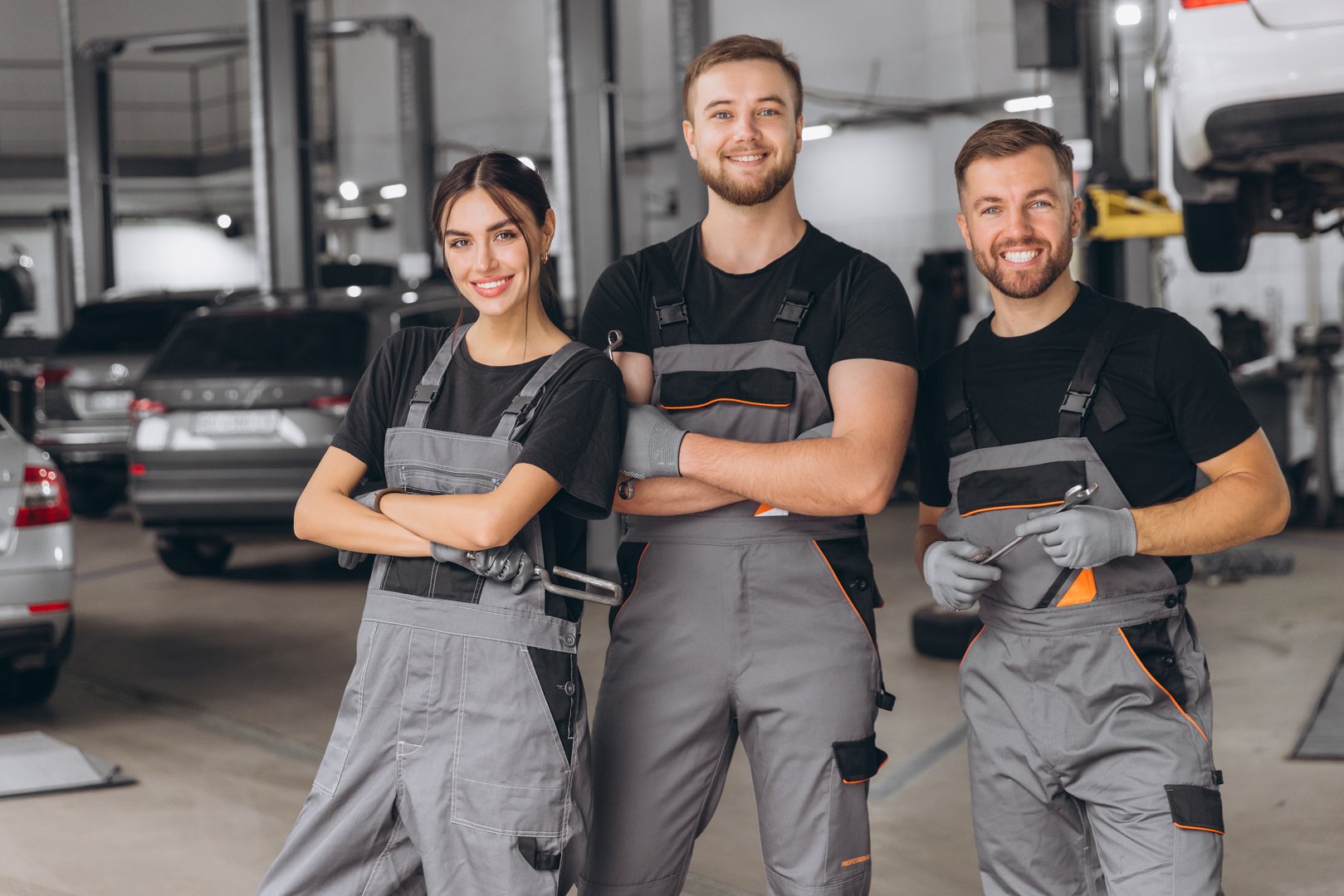 Group of three car service technician men and woman talking at workplace