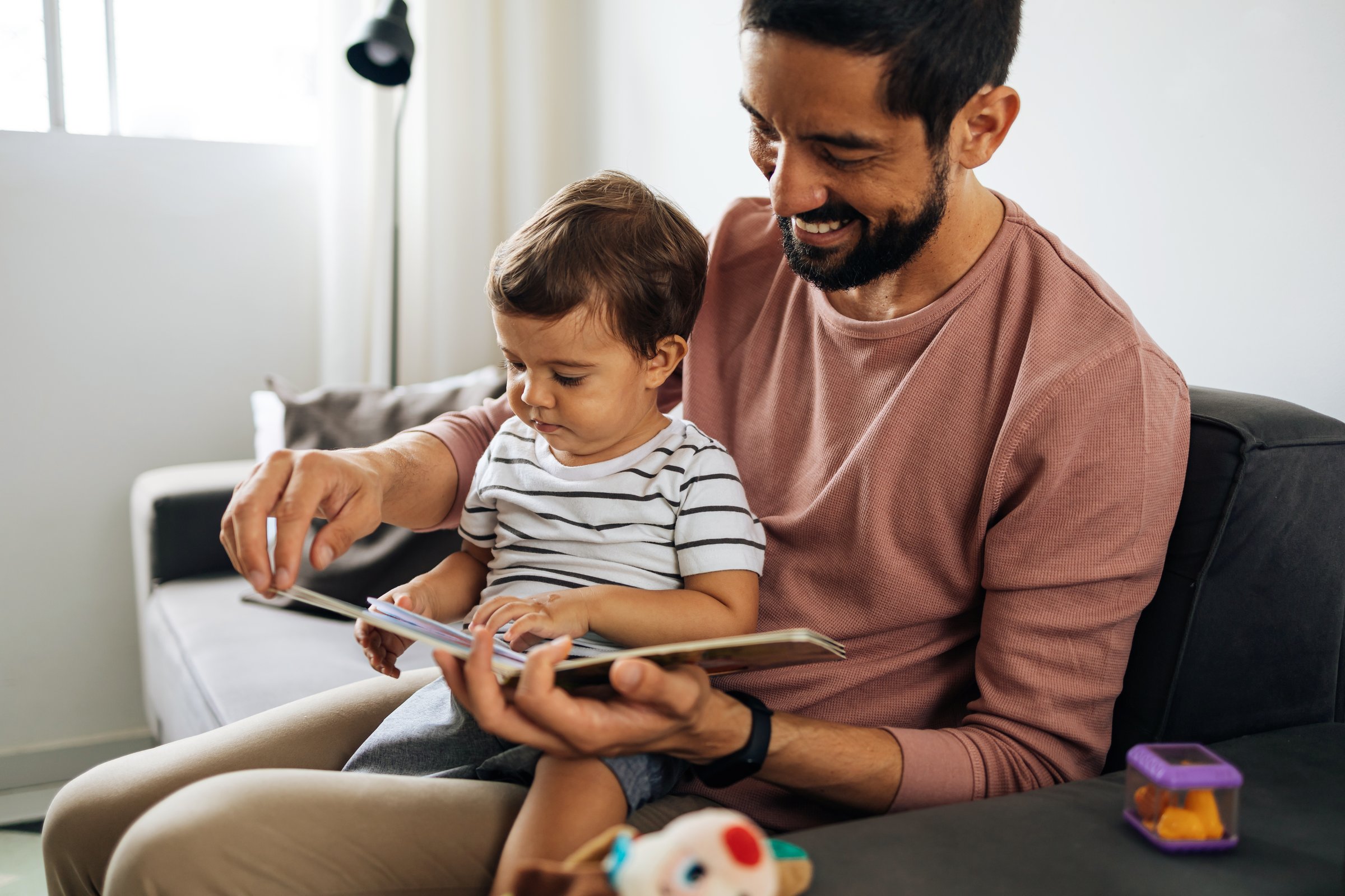 Happy father and toddler son reading book at home