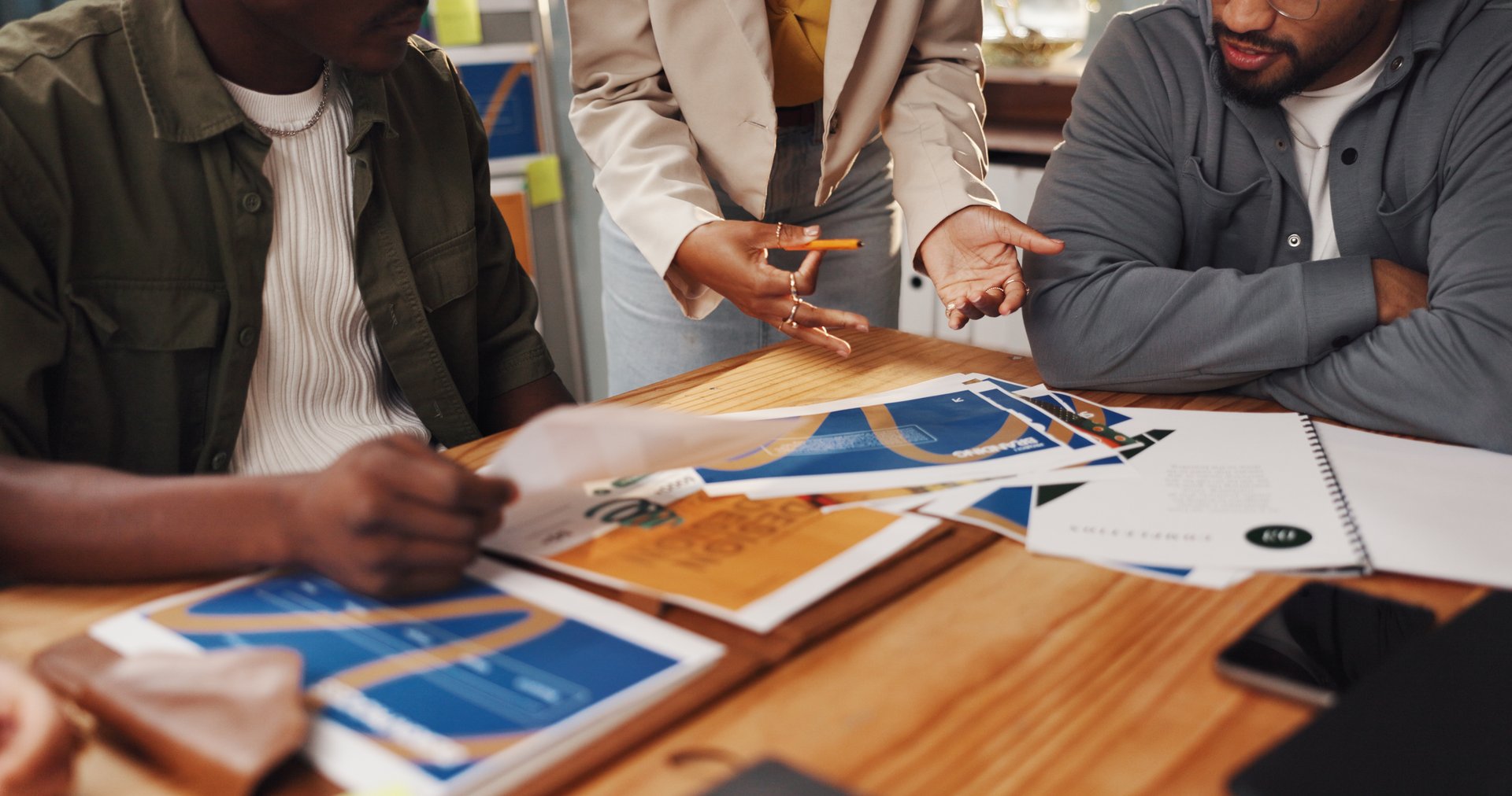 Graphic design, meeting or people with paperwork in office for logo planning, layout draft or ideas. Digital agency, teamwork or creative employees with sample review for campaign feedback or project