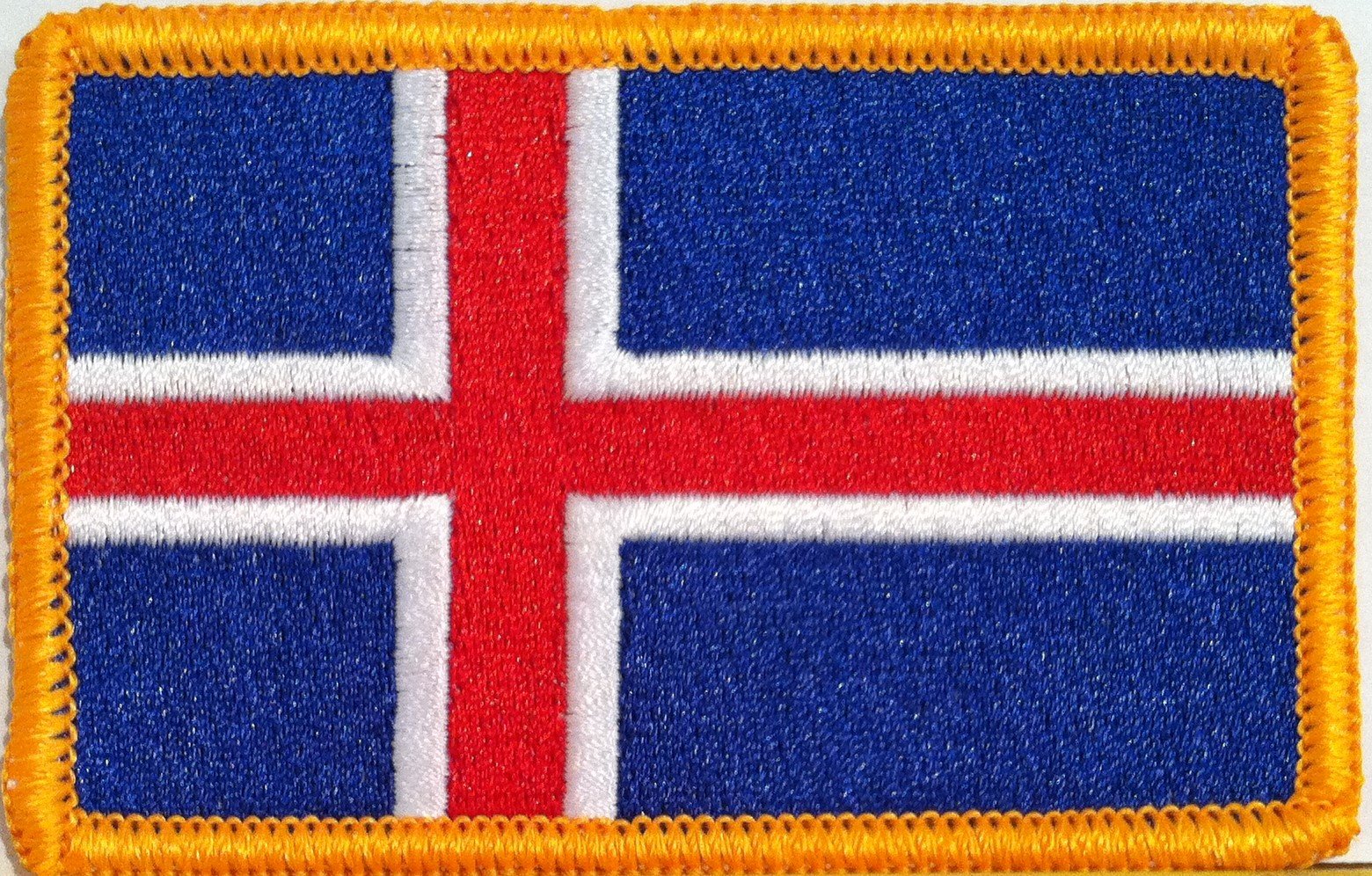 Embroidered patch of the Icelandic flag with a blue background, red cross outlined in white, and a yellow border.