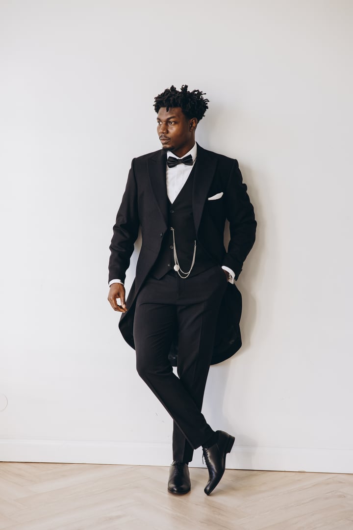 Stylish groom in a sleek tuxedo and bow tie, confidently posing before the wedding ceremony, exuding elegance and sophistication