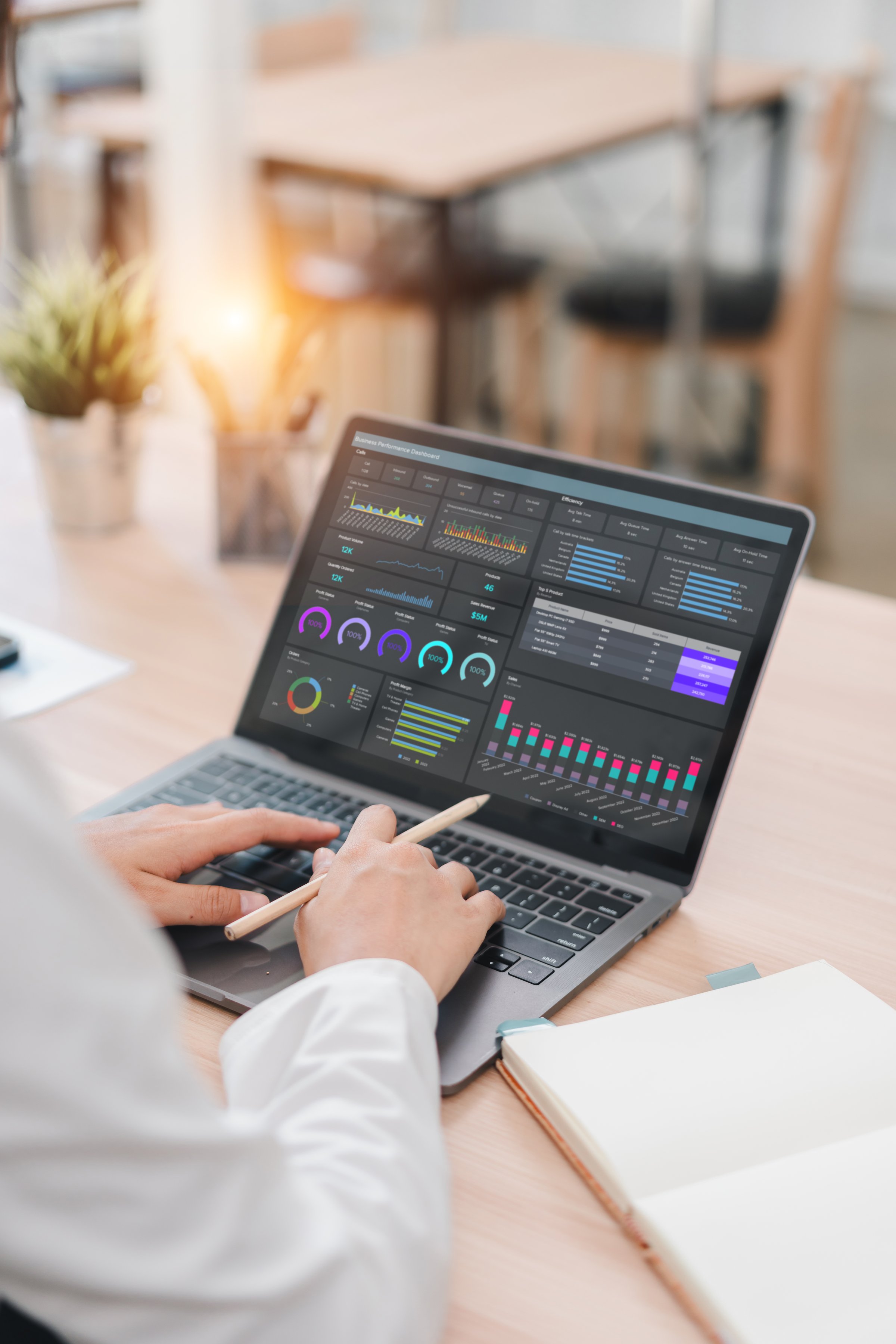 A business professional working on laptop with data analysis dashboard showing graphs and charts, modern office environment, focused and productive atmosphere