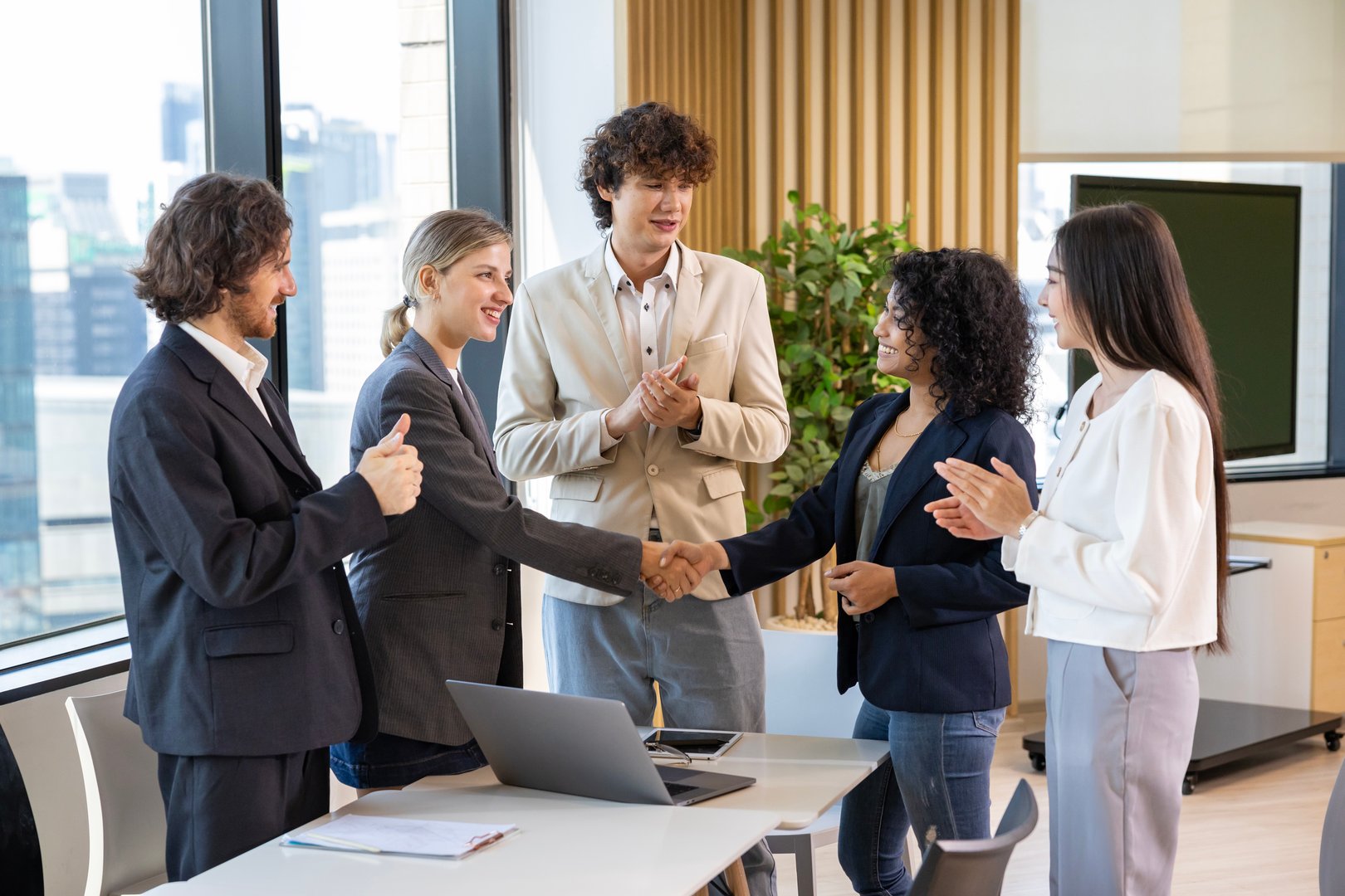 Team of diversity business people having agreement and handshake deal over new strategic strategy project on investment real estate with recognition and applause from other colleagues for partnership