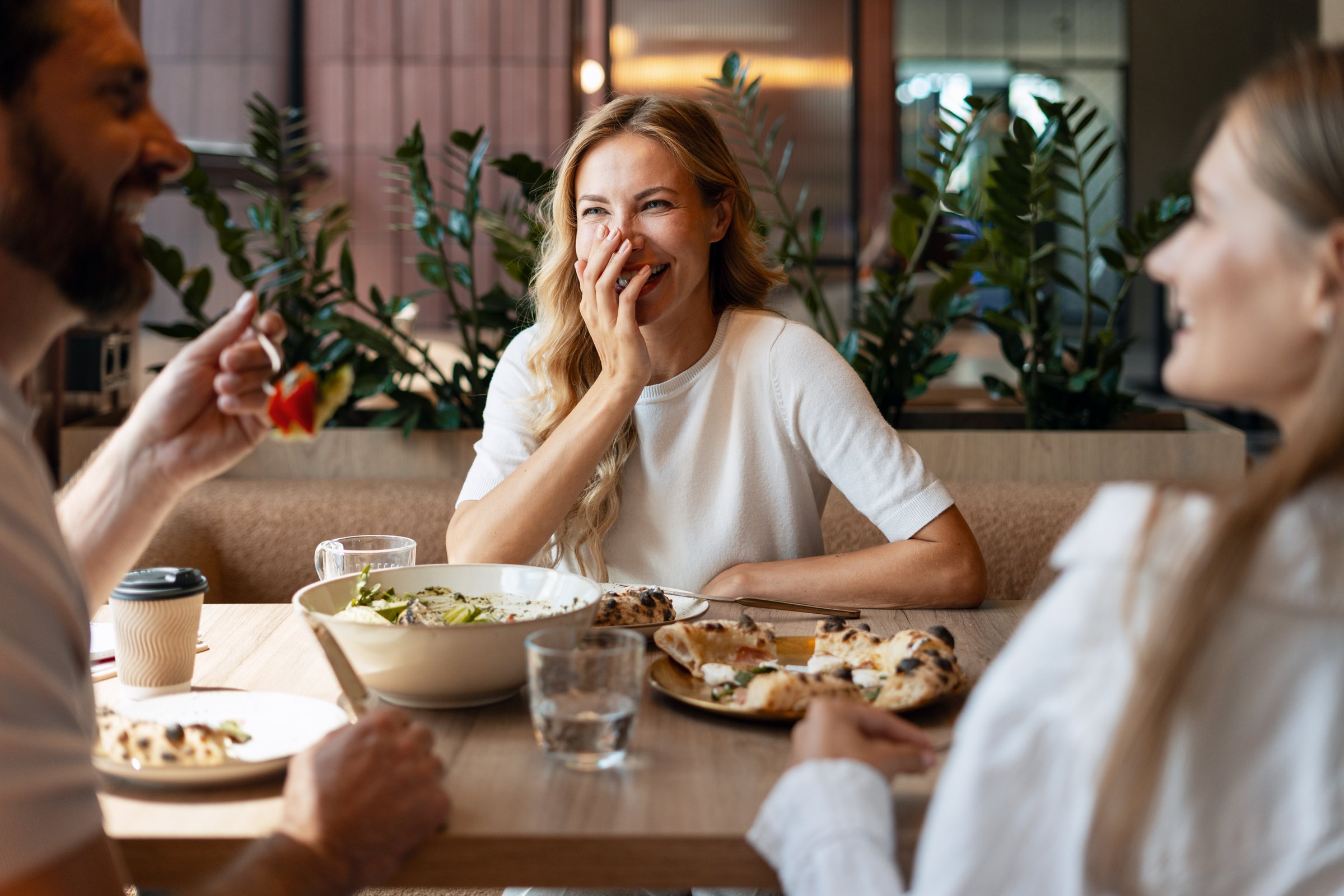 Three friends enjoying a delightful meal at a restaurant, sharing laughter and stories while creating lasting memories together