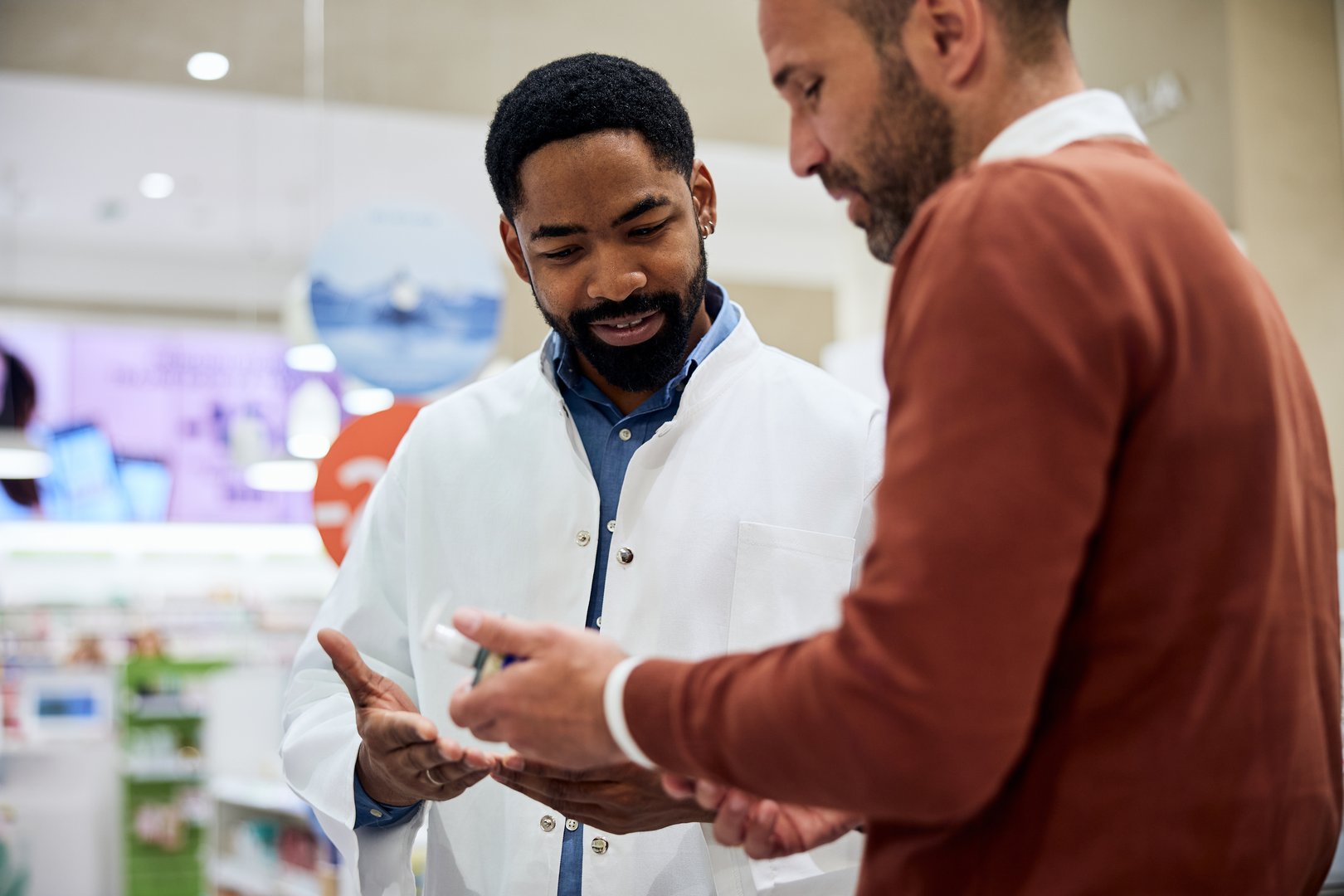 Pharmacist discussing and providing medication advice to a customer in a modern pharmacy.