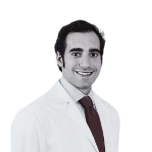 Smiling professional in a white coat and red tie on a plain background.