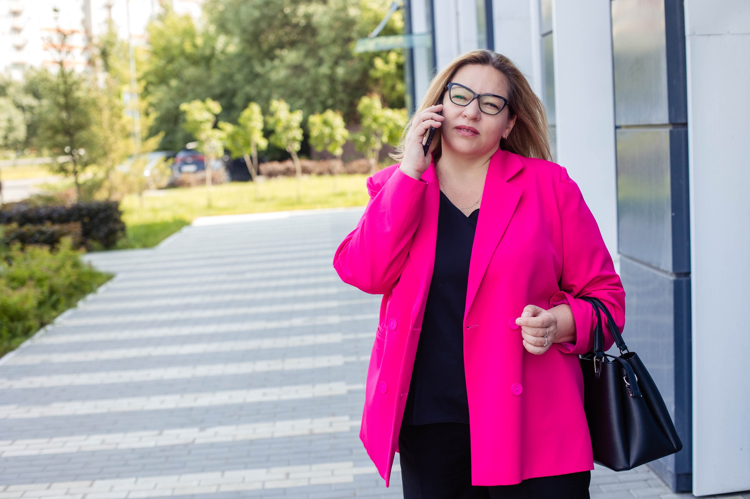 Close-up portrait of a plus size woman, talking on the phone on the street of a modern city.