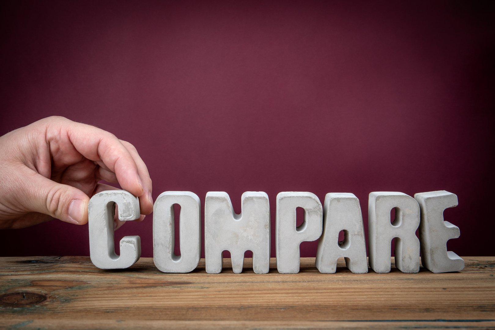 COMPARE Word Created from Concrete Alphabet Letters on Wooden Desk.