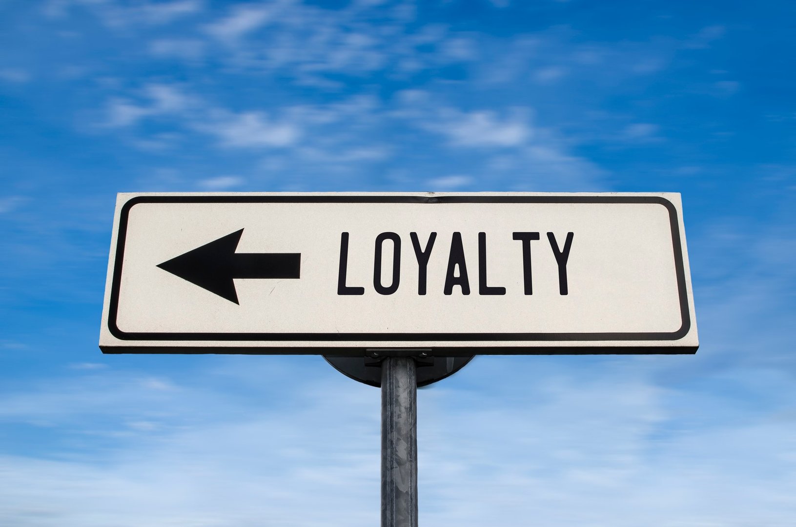 Loyalty road sign, arrow on blue sky background. One way blank road sign with copy space. Arrow on a pole pointing in one direction.