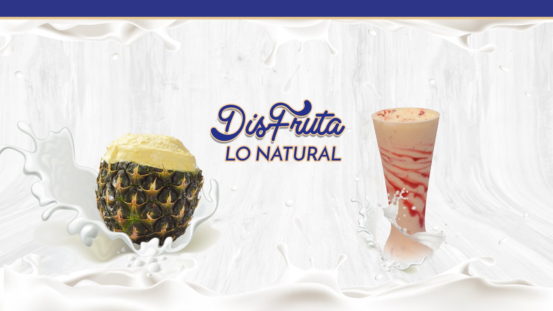 A split pineapple and a smoothie glass splashed with milk, with text: "Dis-Fruta Lo Natural" on a light background.