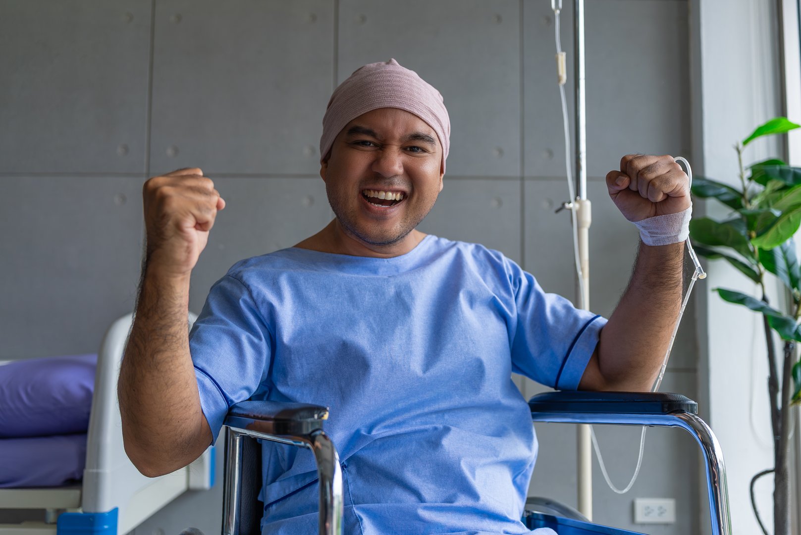 Asian man cancer patient smiling and happy with health checkup result after listening to oncologist explanation while sitting on wheelchair  in hospital ward.