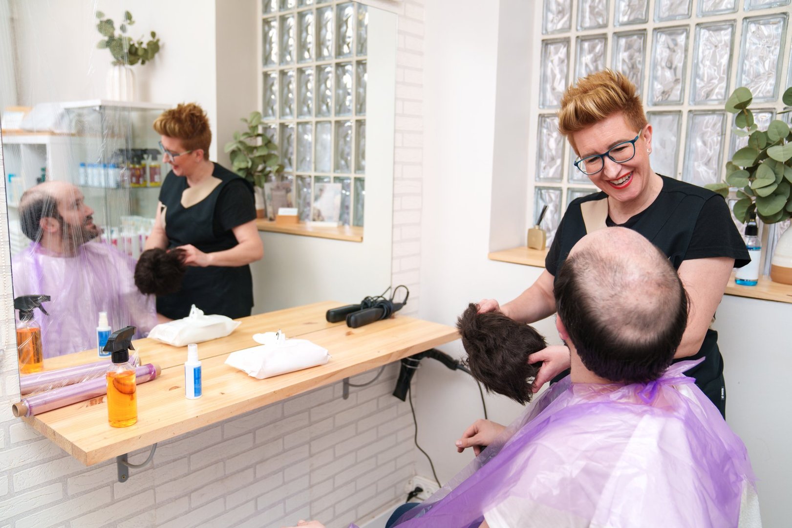 Laughing together as the stylist removes a hair system for maintenance.