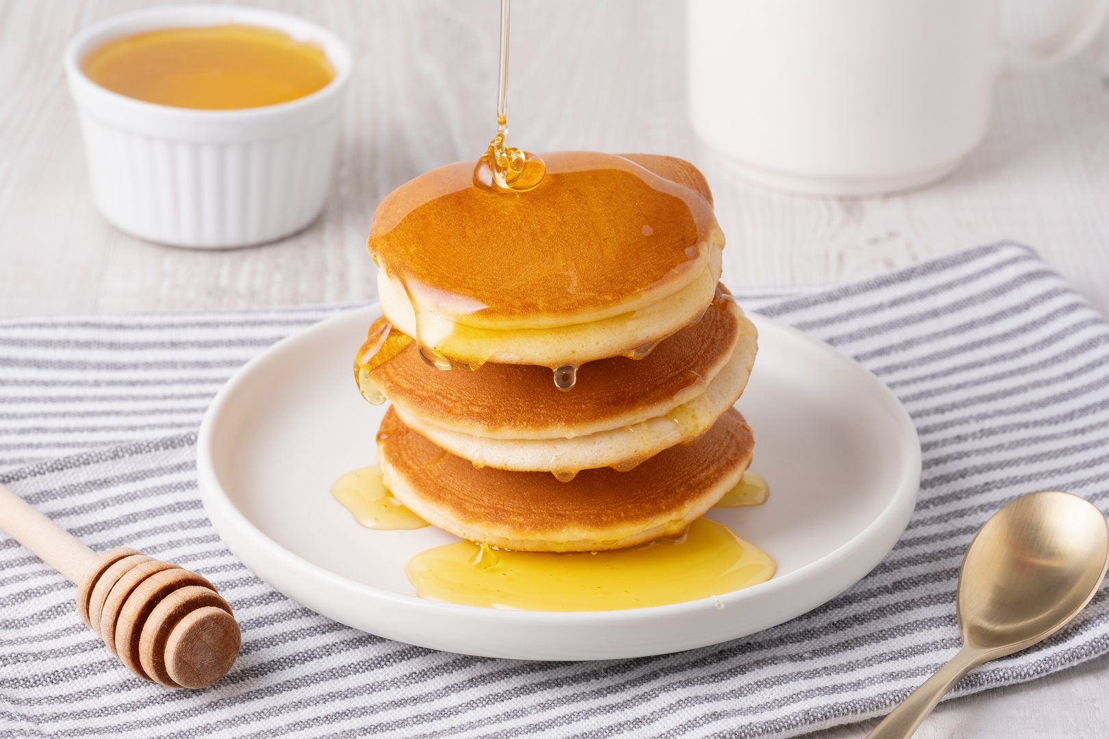Delicious fluffy pancakes with syrup served on a white plate for breakfast.