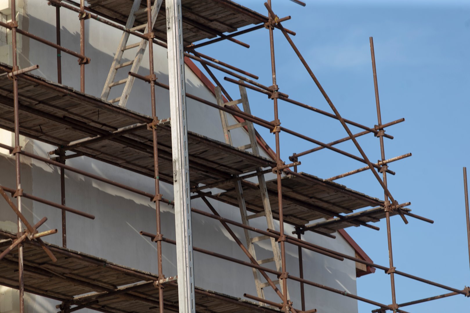A towering building currently in the midst of construction, featuring scaffolding that is securely placed on one side of it for support purposes