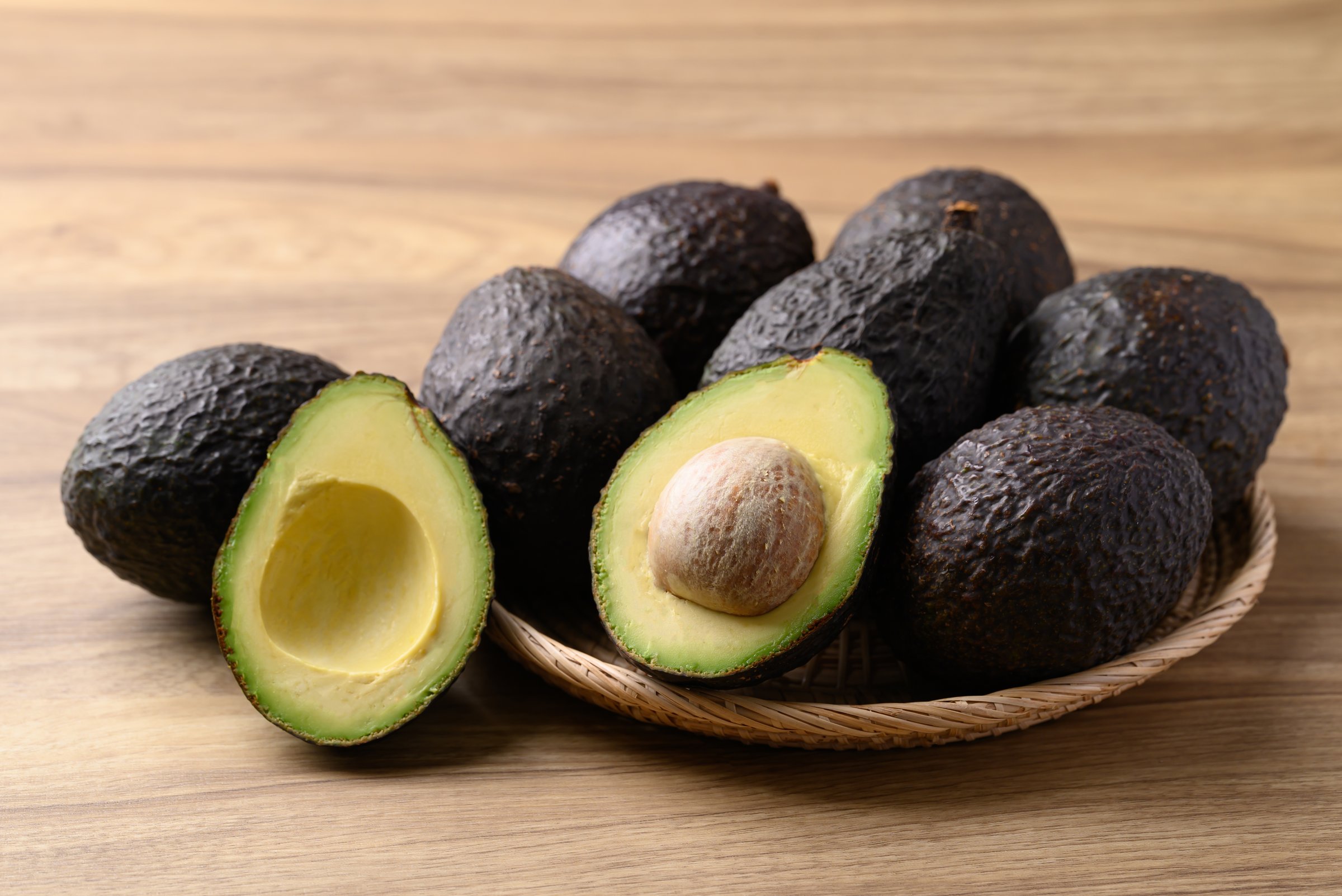 Ripe Hass avocado fruit in basket on wooden background, Healthy fruit