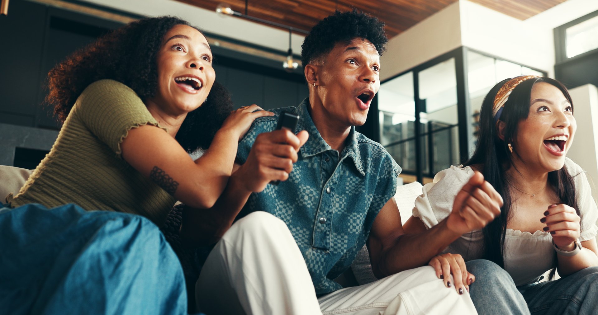 Friends, excited and celebration with watching tv on sofa for sports goal, team support and match success. Football game, people and live streaming tournament in home with winning results and passion