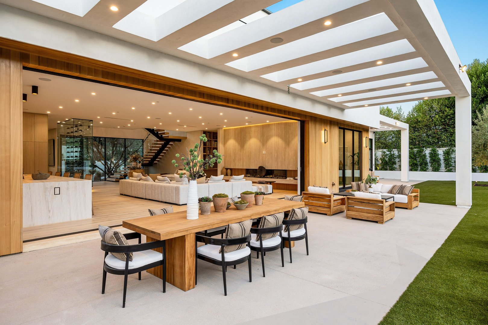 Modern luxury outdoor living space with elegant wooden furniture and open design, featuring a seamless transition to indoor areas.