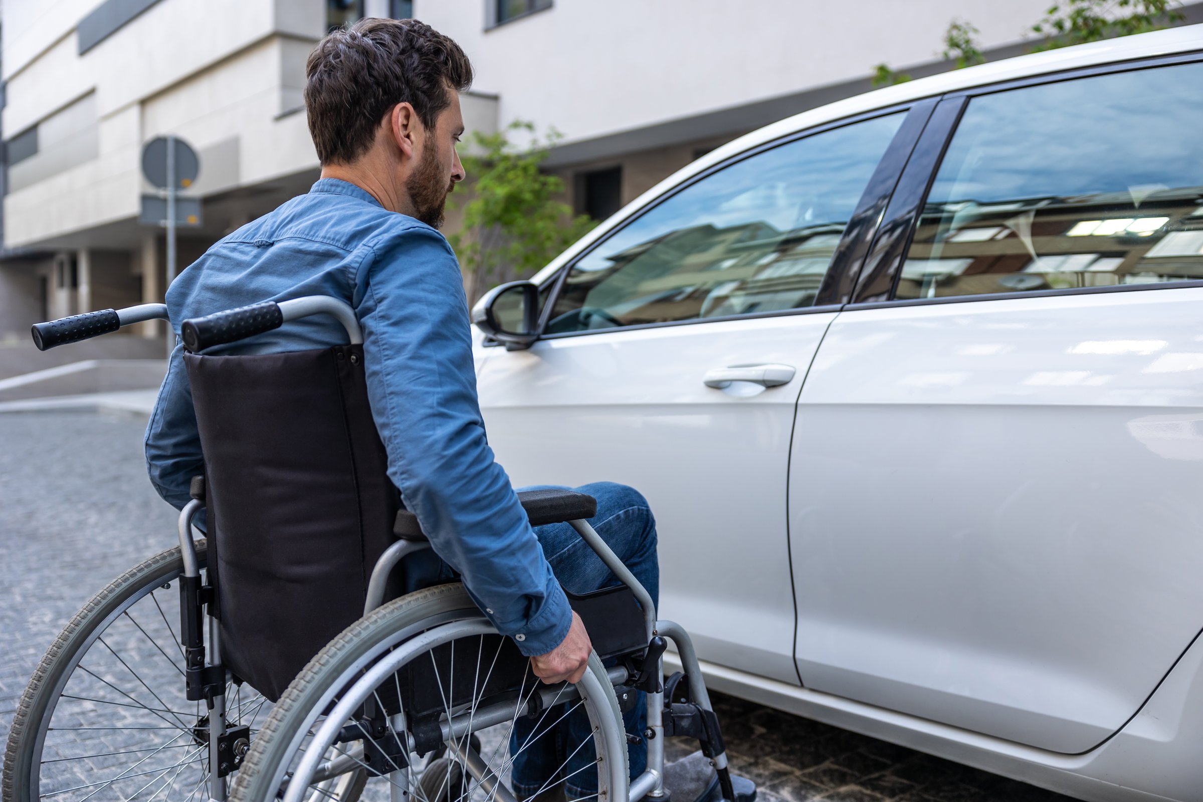 Man near the car. Man in a wheelchair opening a car door