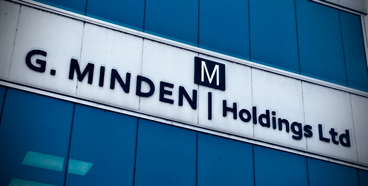 Sign reading G. Minden Holdings Ltd on a blue glass building facade.