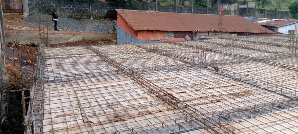 Construction site with a concrete wall, wooden supports, and building materials scattered on the ground.
