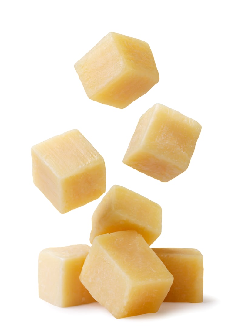 Cheese cubes falling on a pile close-up on a white background. Isolated