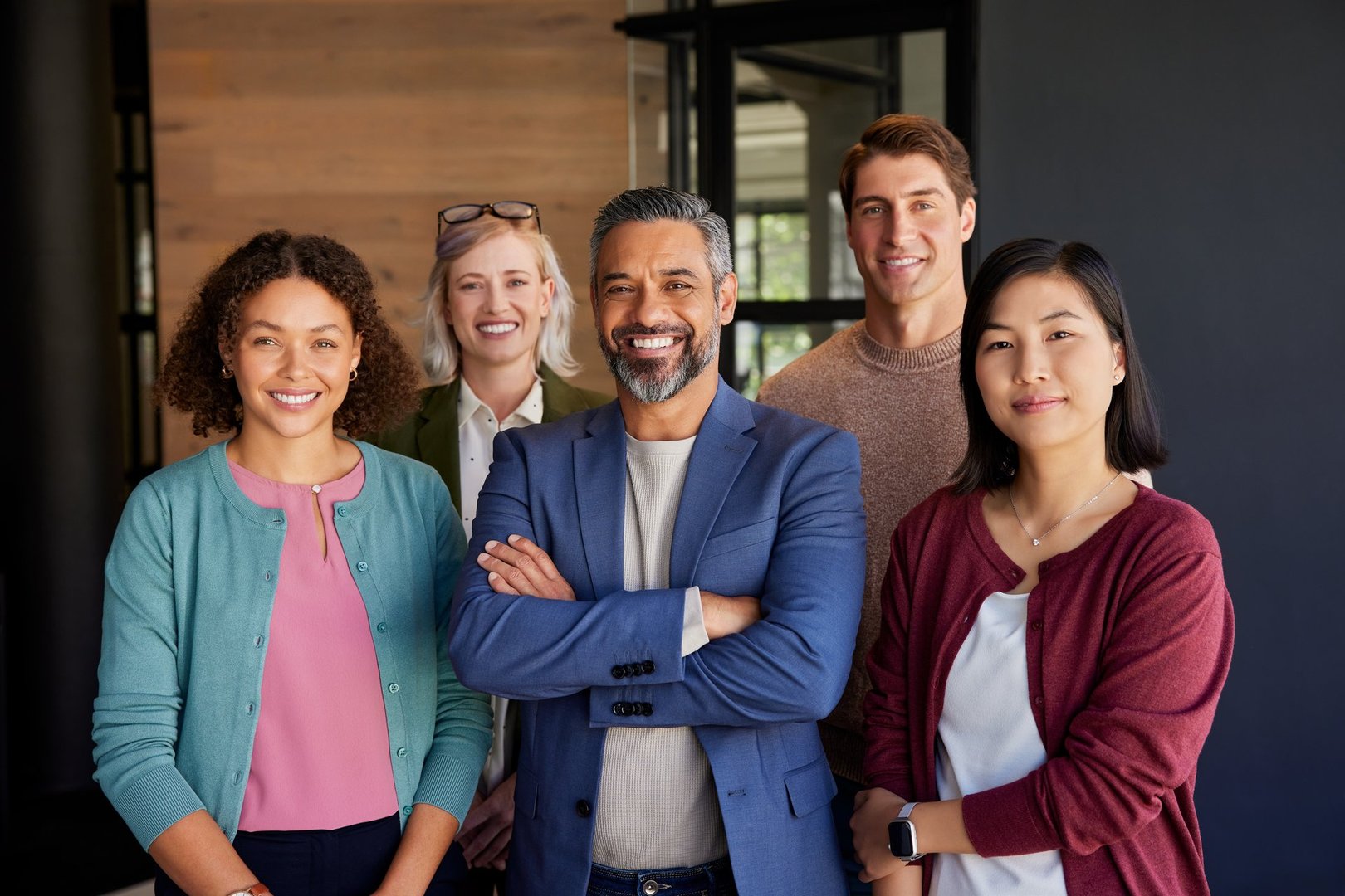 Group of diverse professionals posing in an office environment while smiling and looking at camera. Successful business group posing together at modern office. Middle eastern leadership with his multiethnic team expressing unity and confidence.