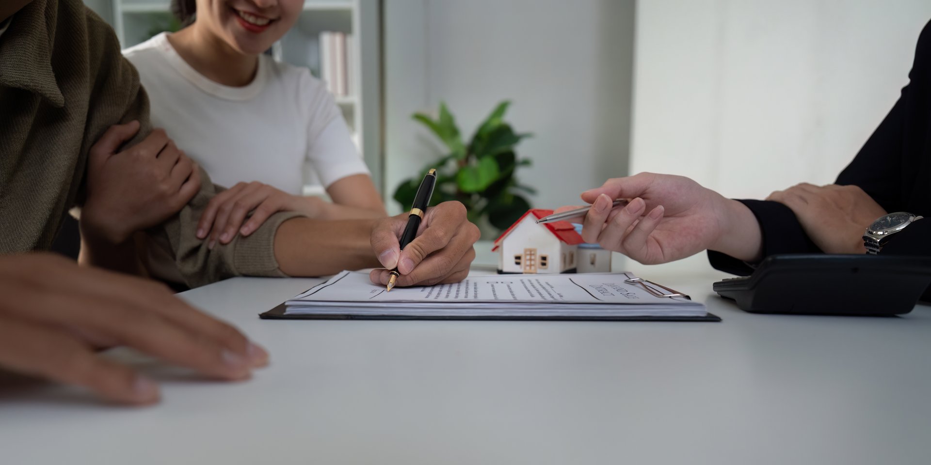 A couple reviews documents with a real estate agent, excitedly preparing sign a contract for their new home. The atmosphere is filled with anticipation and collaboration.
