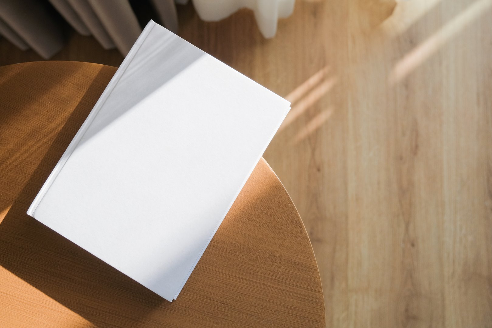 book cover mockup design. blank book template on wooden coffee table in living room or hotel room, shadow overlay