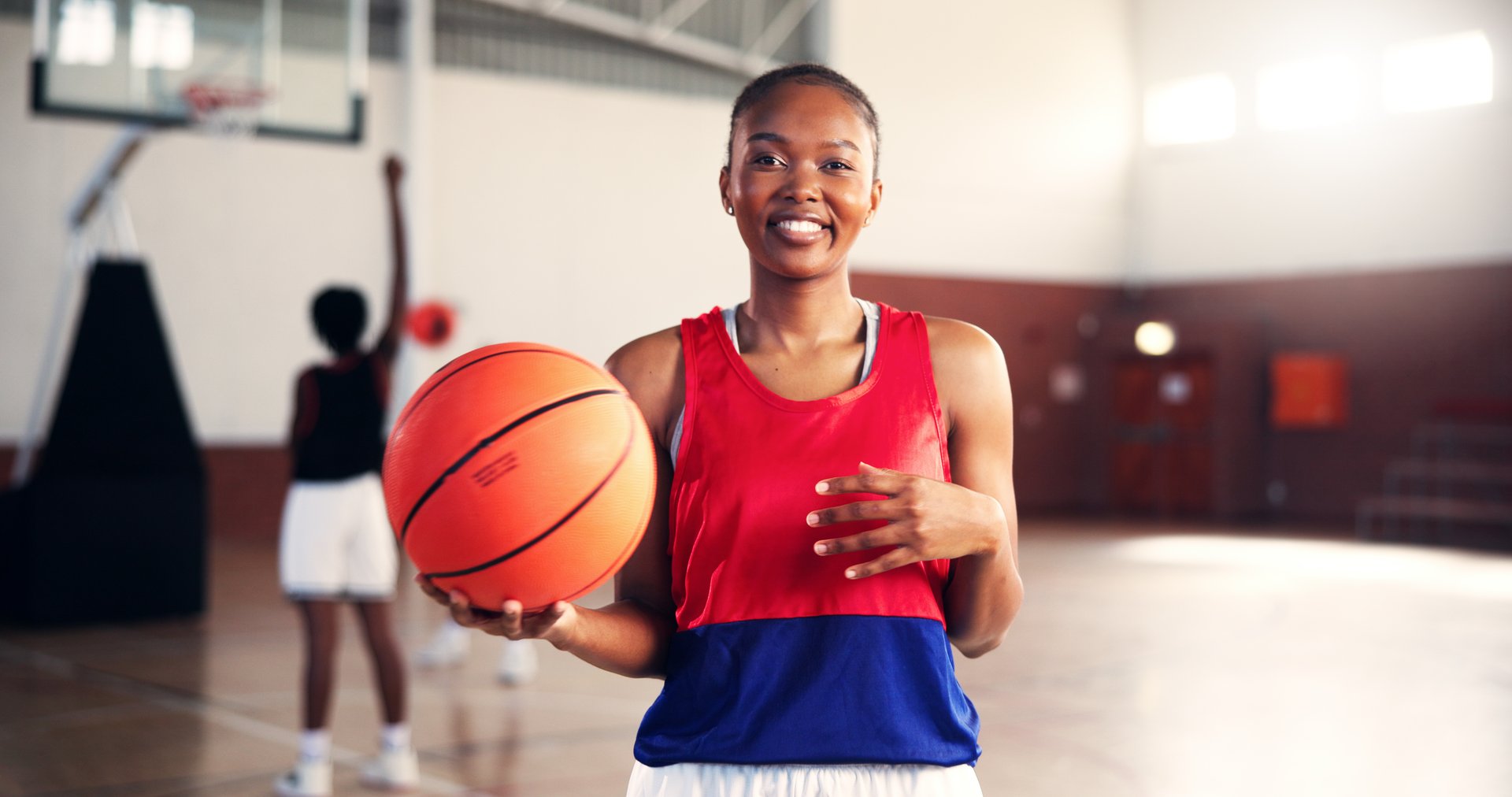 Girl, basketball court and happy in portrait at gym for fitness, confident and ready with training for competition. Woman, start and smile with pride for contest, workout and exercise at sports club