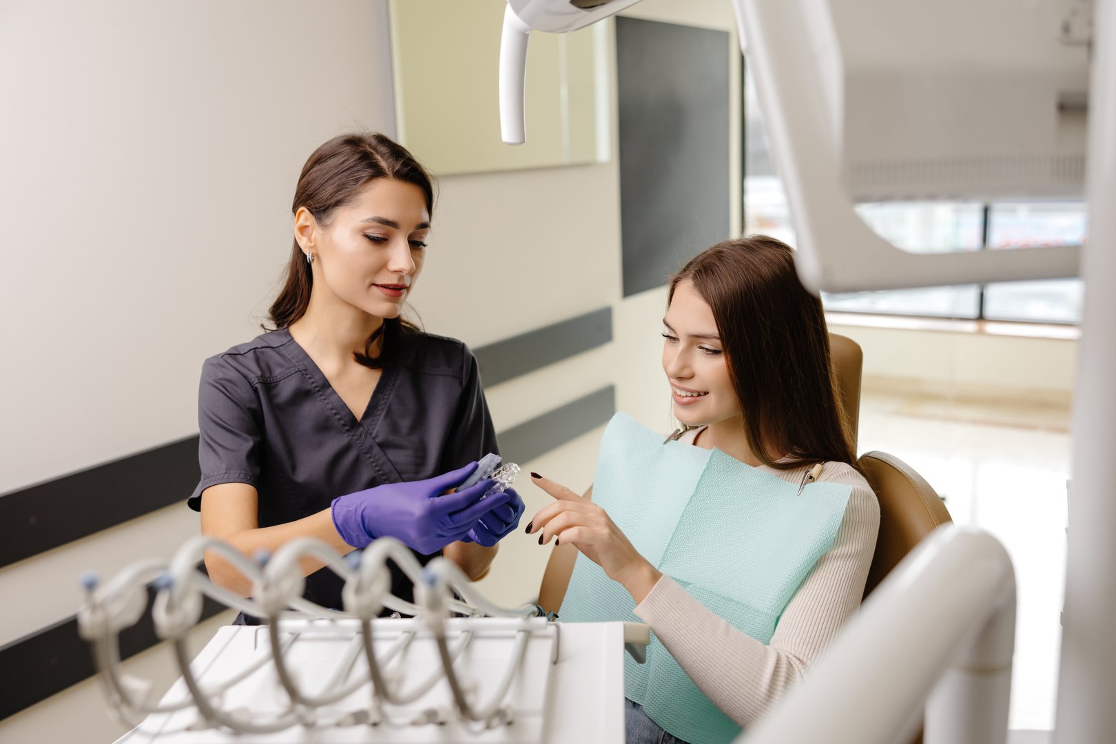 Dentist wearing rubber gloves holding transparent aligners for teeth correction for a patient in dentistry clinic.