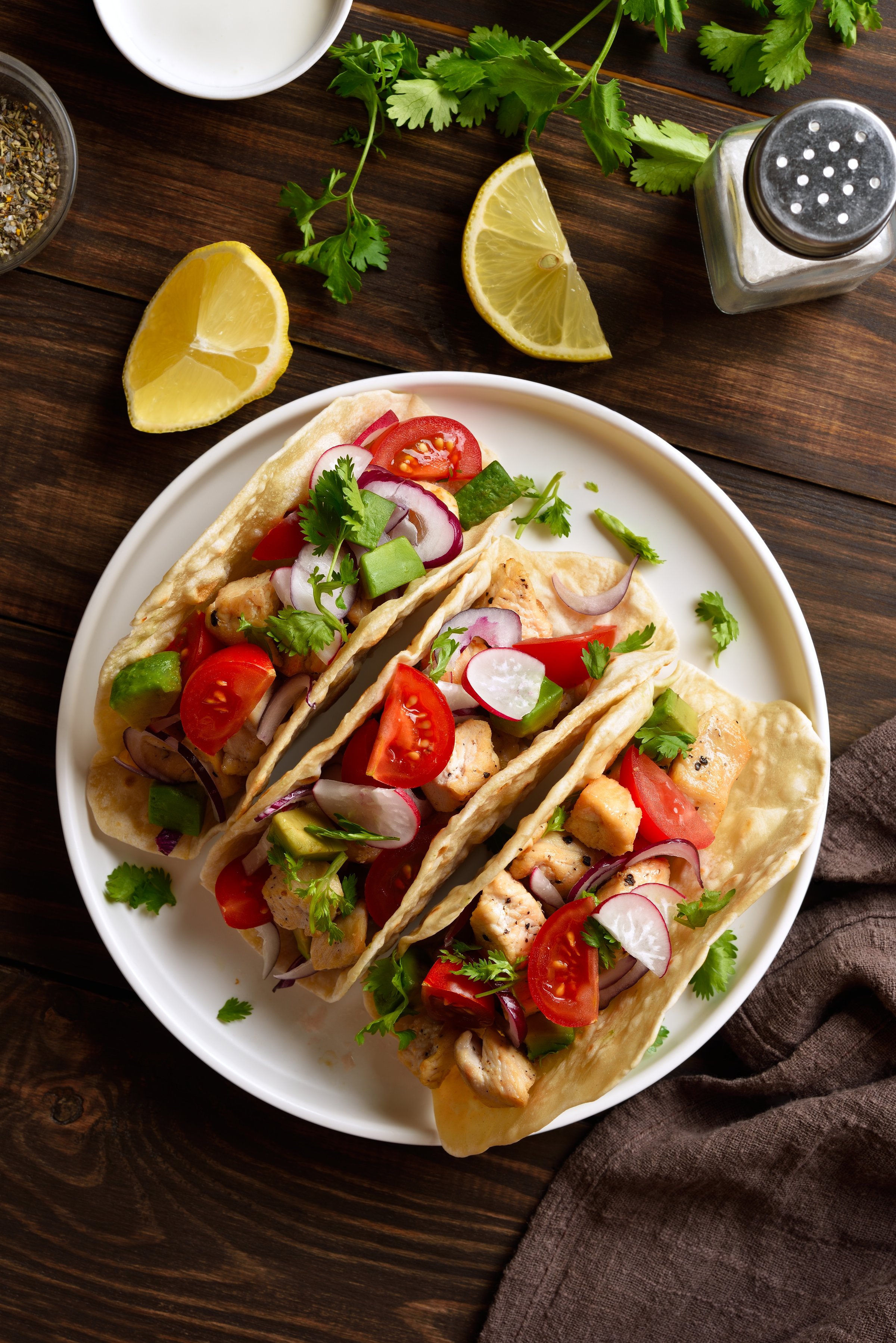 Tacos with vegetables and meat on white plate on wooden table. Top view, flat lay