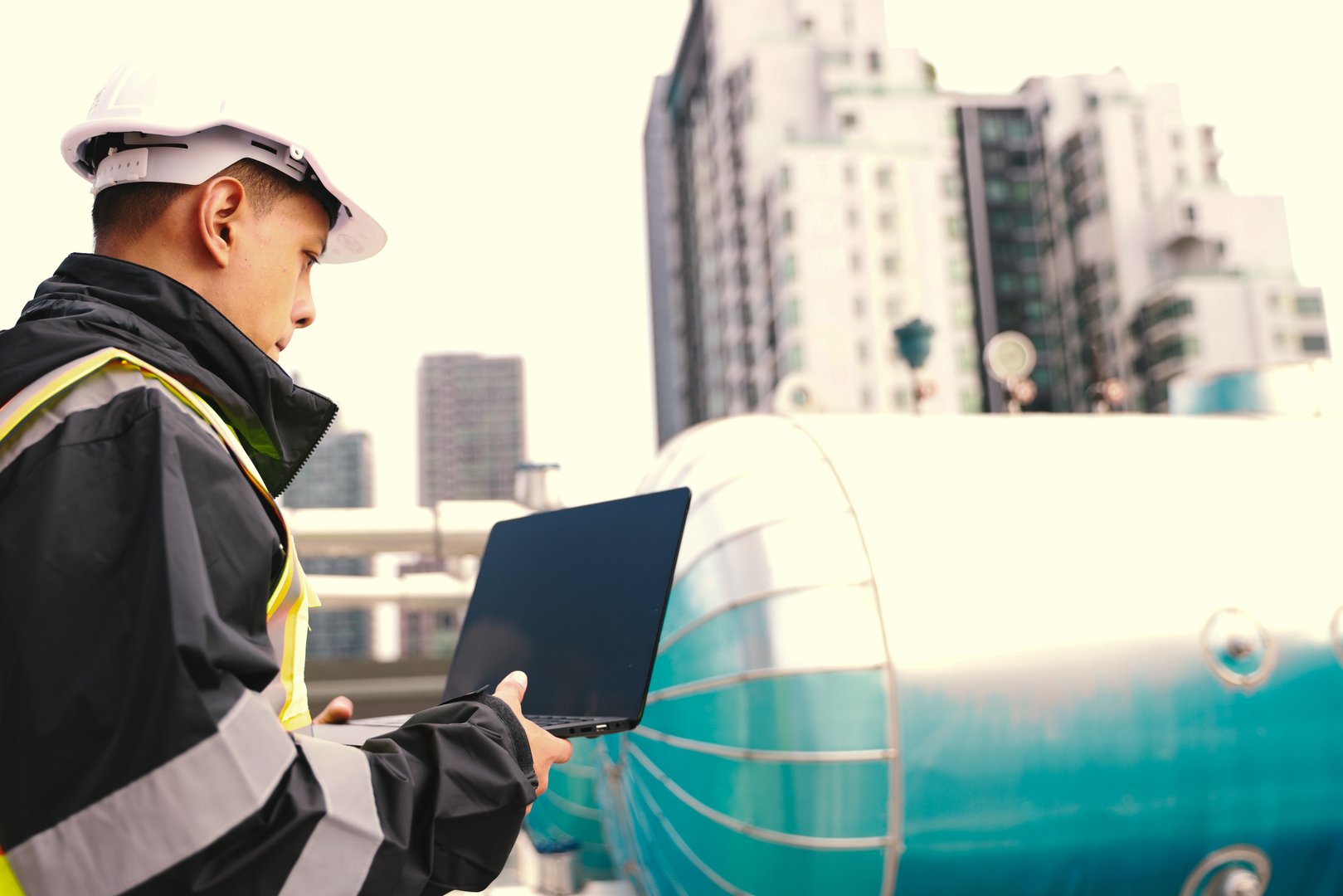 Asian male  HVAC system engineer works on-site to check piping and cooling system on the rooftop of the building