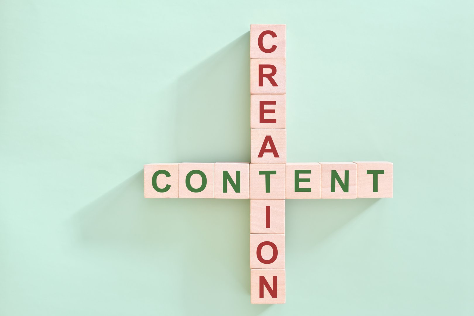 Content creation concept. Wooden blocks flat lay typography composition in green background.